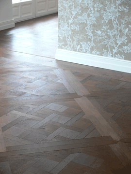 Parkettboden mit einem geometrischen Muster in einem hellen Raum.