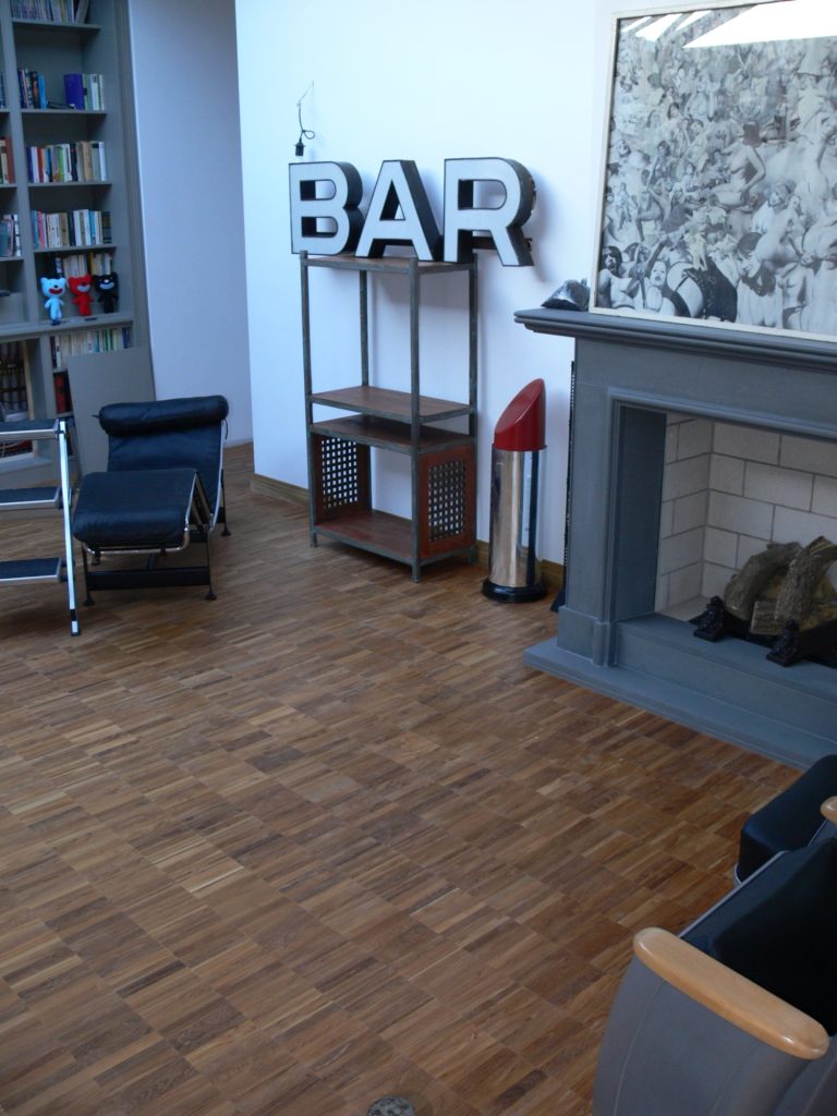 Moderne Wohnraum mit Holzfußboden, einer Bar und einem Kamin.