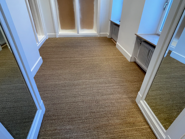 Ein heller Umkleideraum mit mehreren Spiegeln und einem neutralen Teppichboden.