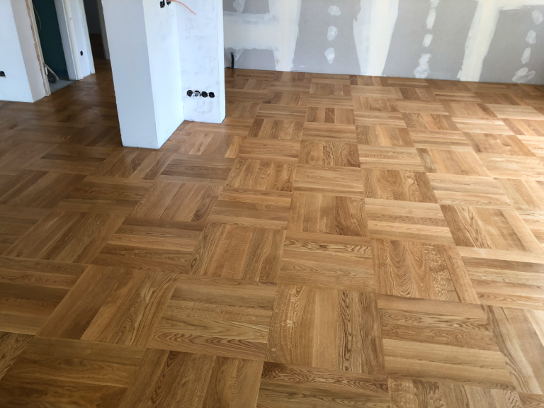 Holzboden im Fischgrätmuster, hell, in einem unfertigen Raum.