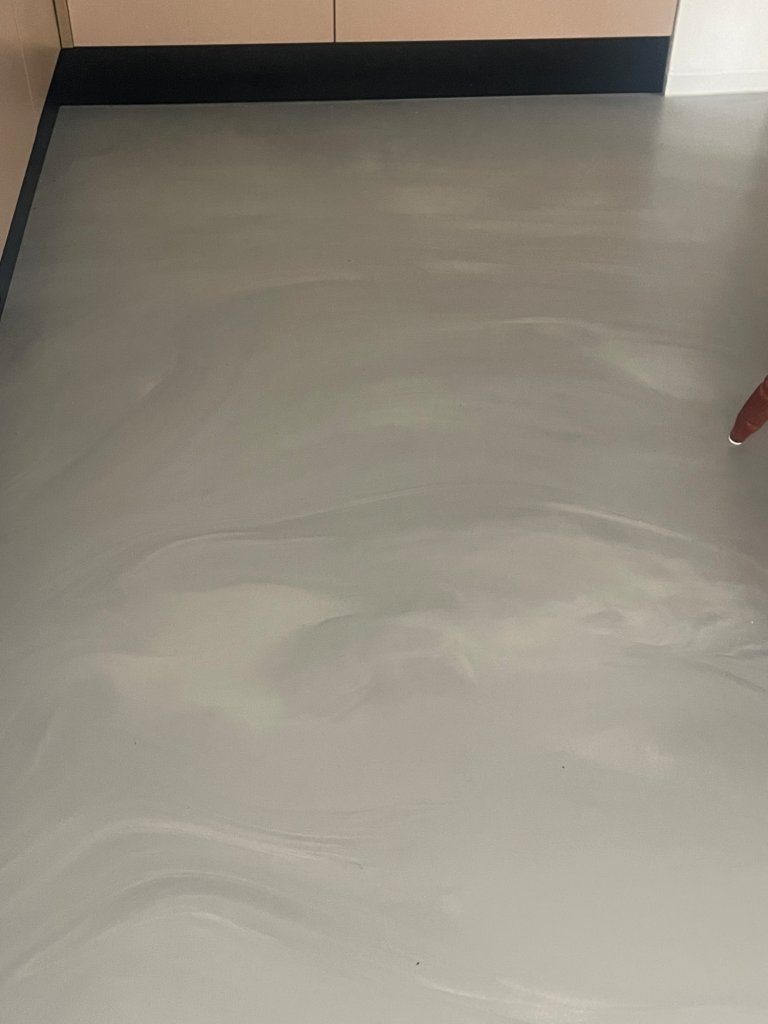 Glatte, helle Bodenfläche mit sanften, marmorierten Mustern in Grau und Weiß.