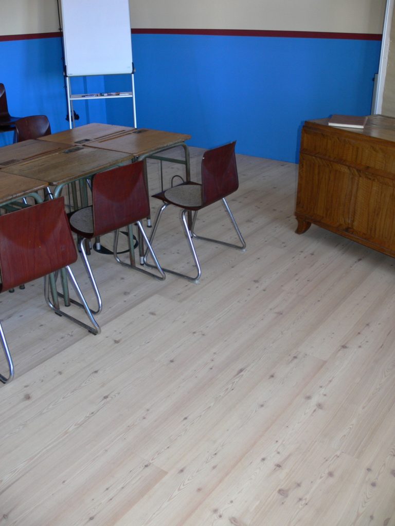 Ein Klassenzimmer mit einem Tisch, Stühlen und blau gestrichenen Wänden.